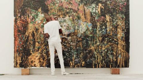 Mark Bradford working on a large, abstract painting.